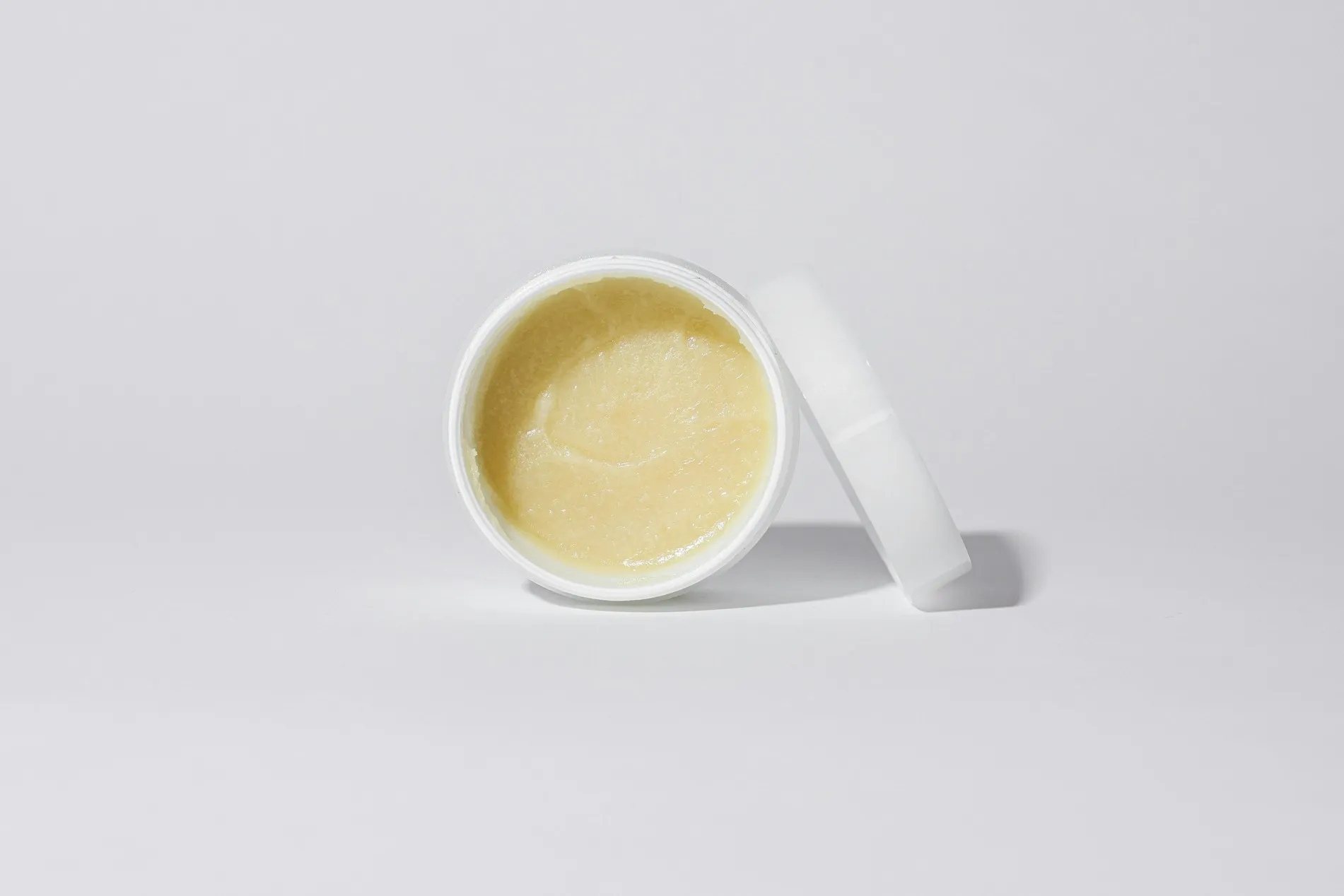 Shea butter moisturizer in an open jar on a white background