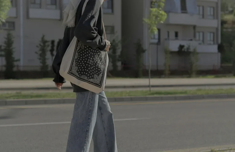 Person wearing casual streetwear and carrying a patterned tote bag on a city street, reflecting tote bag culture