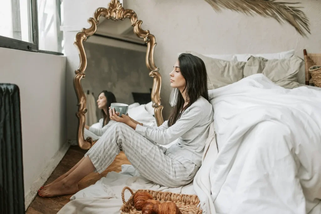 Woman doing affirmations in the morning, next to her bed