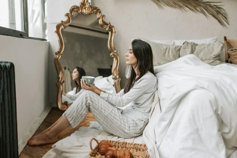 Woman doing affirmations in the morning, next to her bed